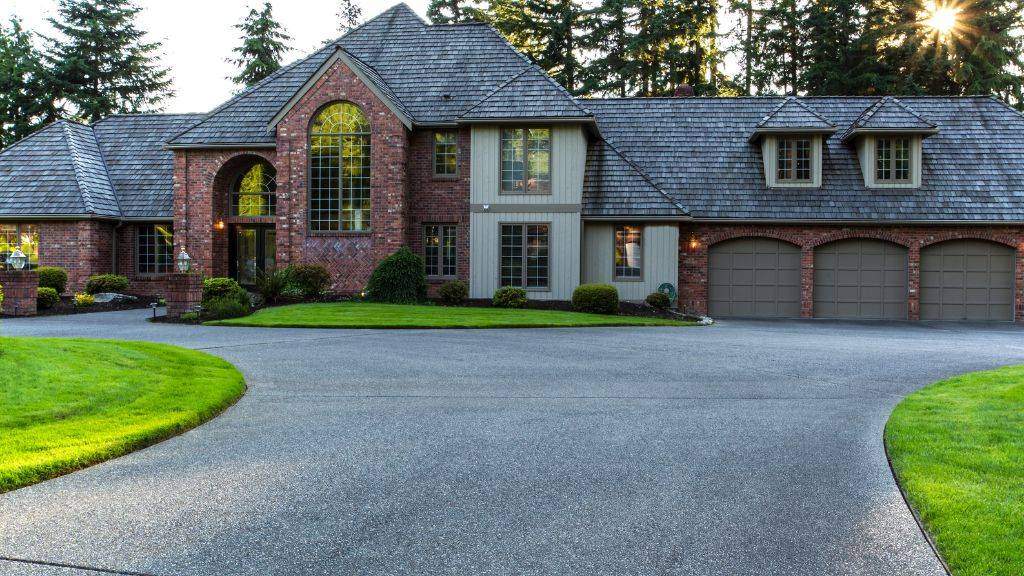 Smooth, newly paved asphalt circular driveway leading to a luxury brick home.
