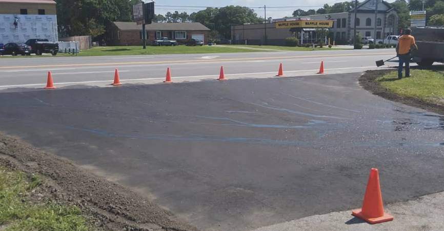 Freshly applied asphalt sealcoating on a commercial entryway lined with traffic cones in Kinston NC.
